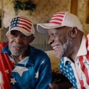 Albert Brayboy Sr. and Albert Brayboy Jr. sit next to each other, cld in U.S.A. merchandise.