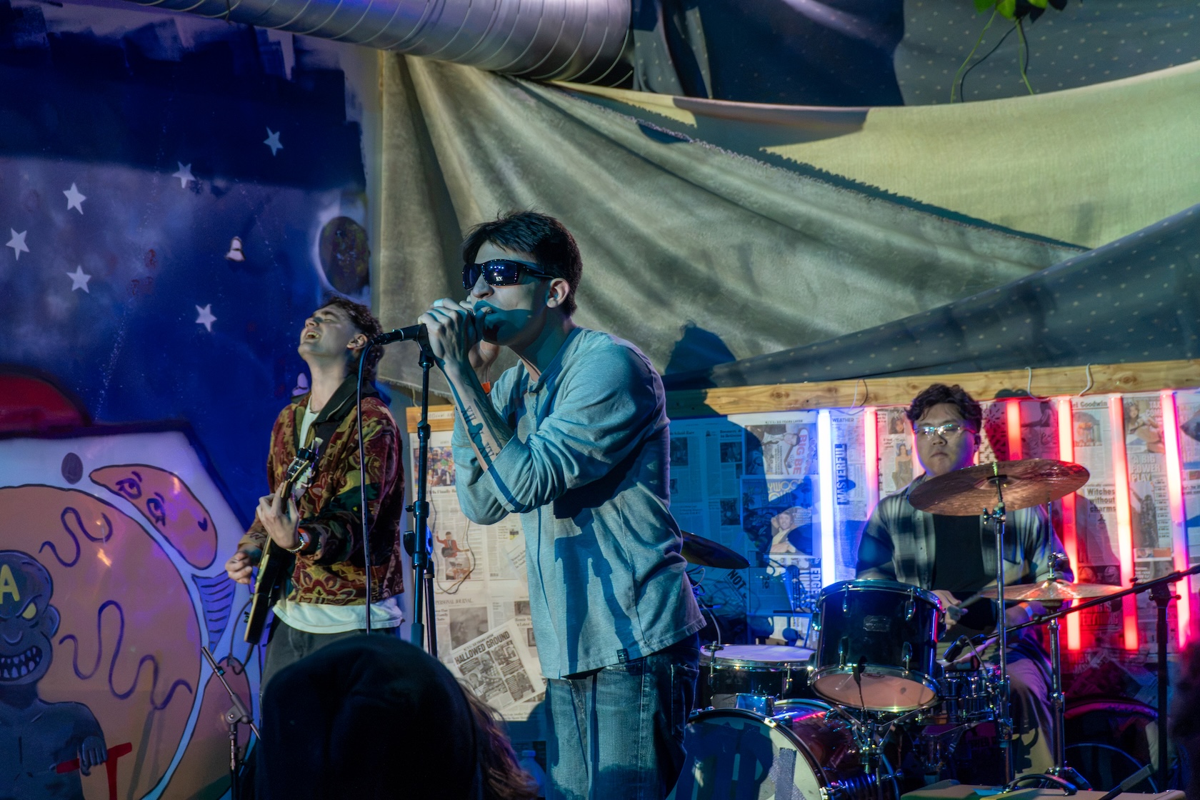Lucaa sings into a microphone while wearing sunglasses.