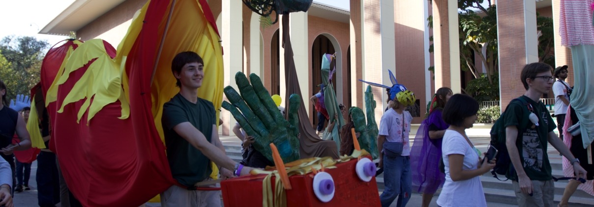 Person walking with long orange and red dragon puppet.