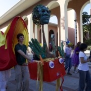 Person walking with long orange and red dragon puppet.