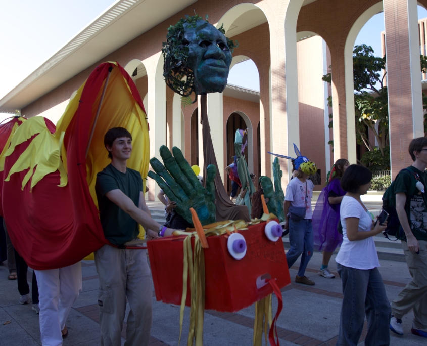 Person walking with long orange and red dragon puppet.