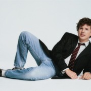 Charlie Puth laying down wearing a suit and tie.