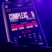 A large display screen shows a concert lineup.