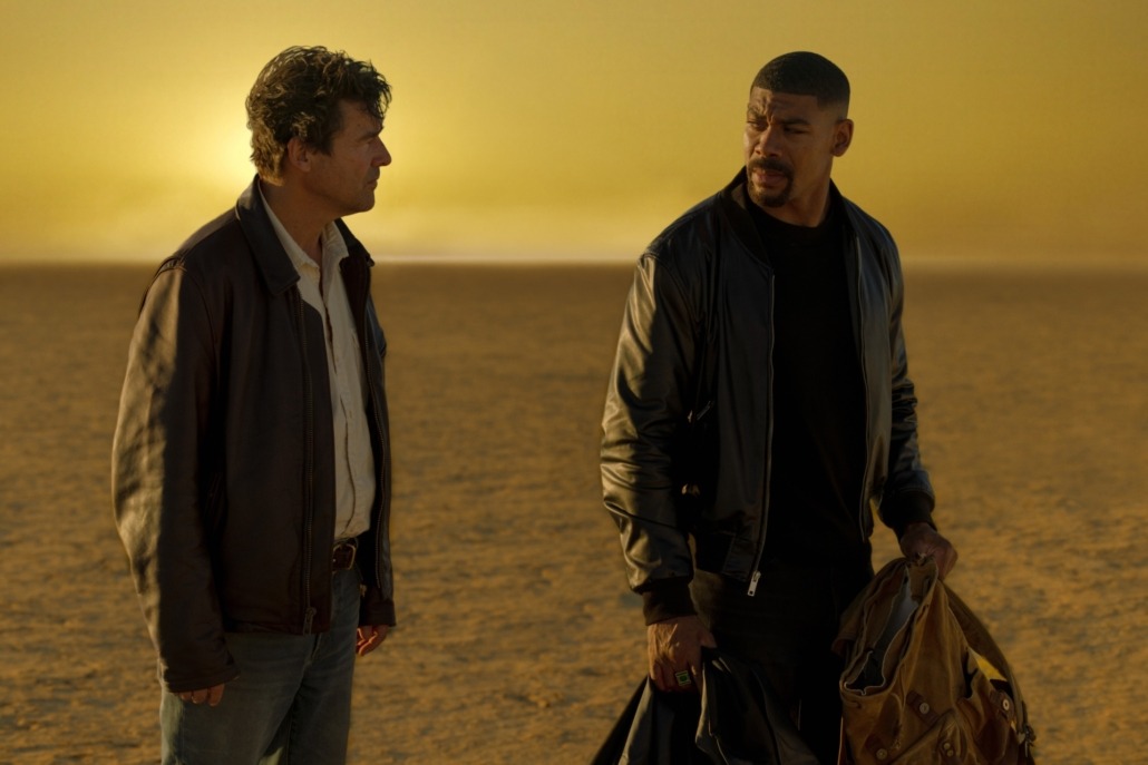 Hal Jordan (Kyle Chandler) and John Stewart (Aaron Pierre) walk in a deserted atmosphere at golden hour.